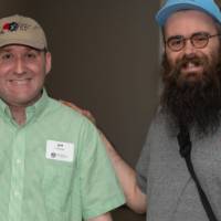 Two guests in hats smile and pose for a photo